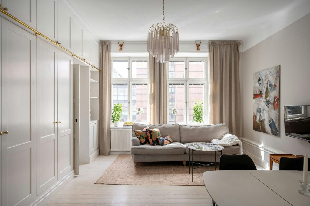 A stylish living room with a sofa, large windows, and sanitized furniture, emphasizing how Apartment Sanitization Service creates a healthy and inviting atmosphere.