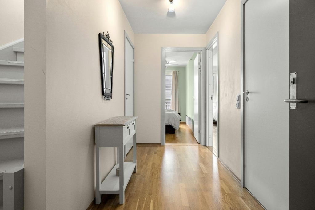 Sunlit hallway with wooden floors and staircase leading to bedroom, showcasing cleanliness supported by Weekend Cleaning Hacks.