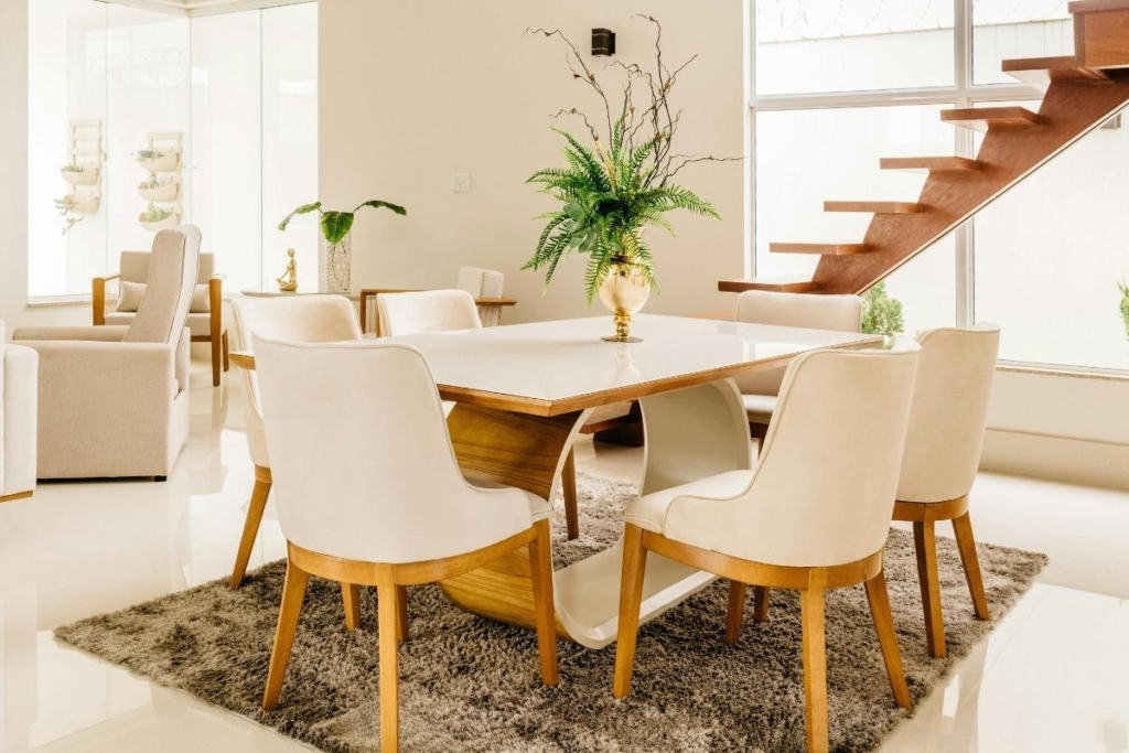 A white dining table and textured rug in a home interior where dust returns after cleaning on furniture.