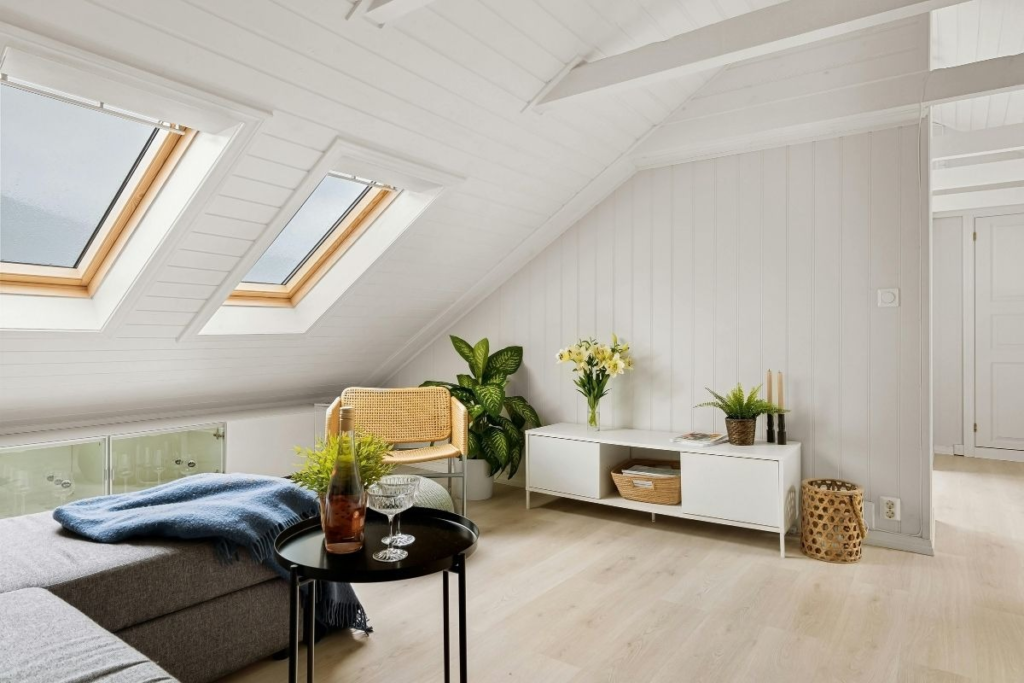 Bright attic room with skylights, sofa, and plants showing a fresh, organized home maintained using Weekend Cleaning Hacks.