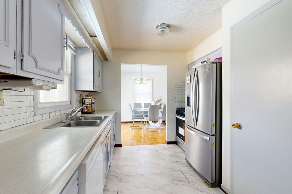 Bright kitchen with gray cabinets and stainless steel appliances showing results of professional appliance cleaning in a modern home.