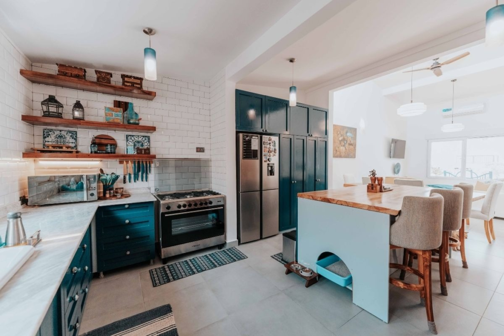 Modern kitchen with blue cabinets, subway tiles, and island seating highlighting a clean space maintained through appliance cleaning services.