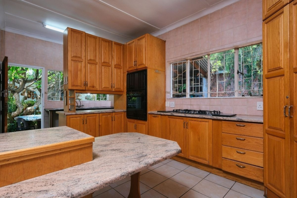 Classic kitchen with light oak cabinetry, granite countertops, and tile flooring.