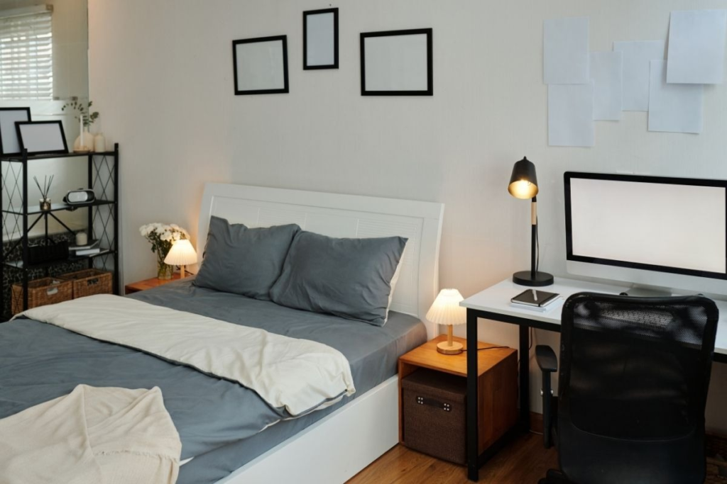 Modern bedroom with a white bed frame, grey bedding, and a minimalist home office desk.