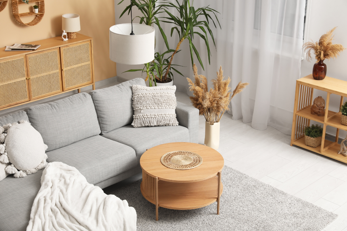Cozy modern living room styled with warm neutral tones, featuring a grey sofa, wooden coffee table, and pampas grass decorations.